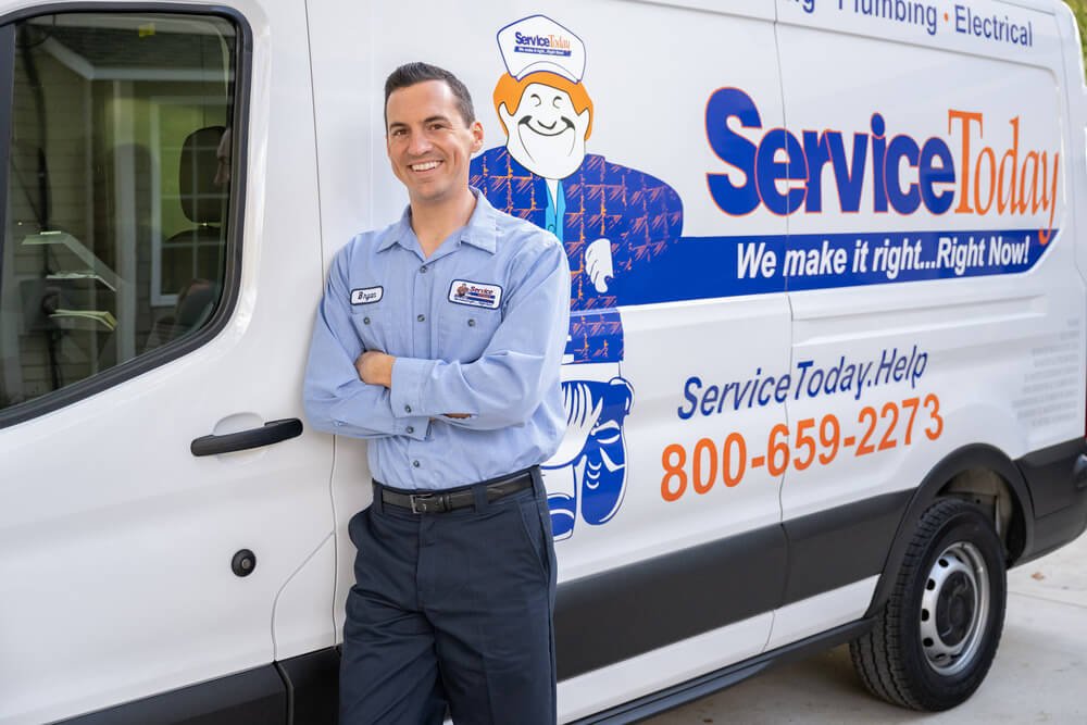 Technician standing in front of branded Service Today truck, smiling.